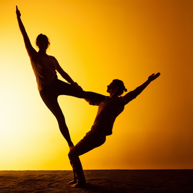 Free photo two people practicing yoga in the sunset light