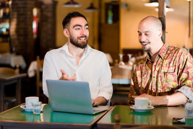 Free photo two people using a laptop on a meeting at a coffee shop.