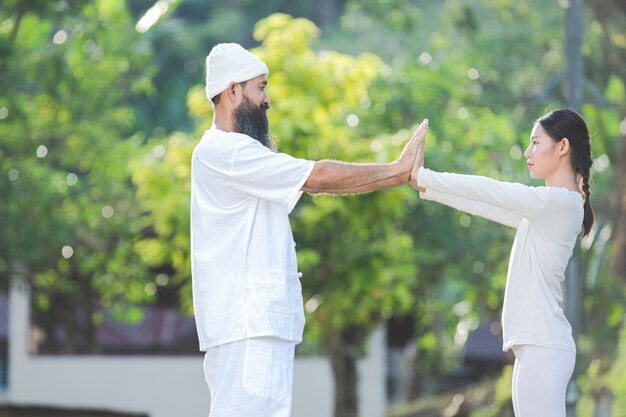 Two people in white outfit doing yoga in nature