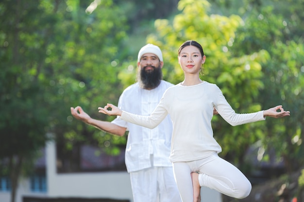 Two people in white outfit doing yoga in nature