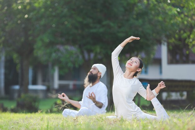 Two people in white outfit doing yoga in nature