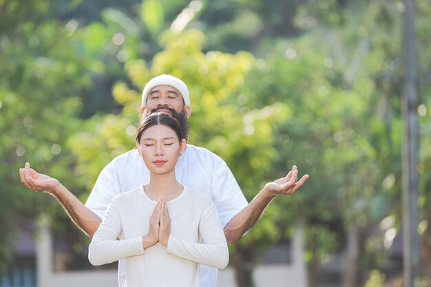 Two people in white outfit meditating in nature