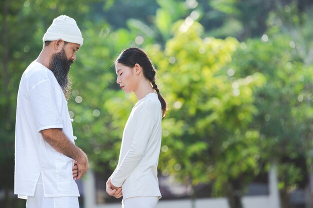 Two people in white outfit meditating in nature