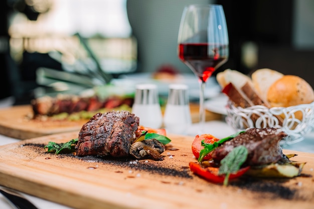 Two pieces of medium cooked steak served with tomato mushroom and zucchini