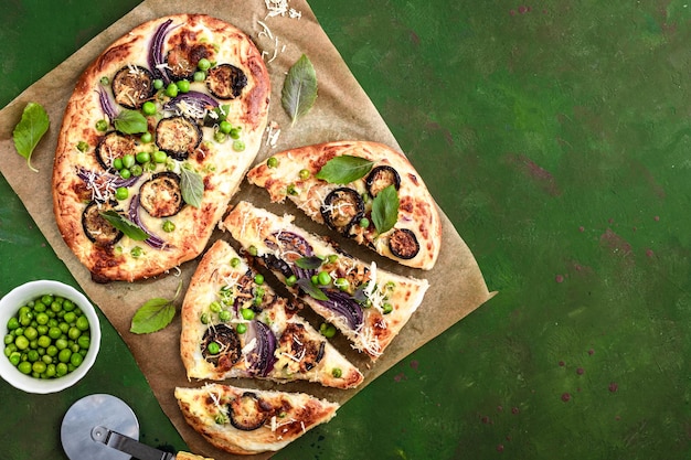 Free photo two pizzas with eggplant green peas and red onion top view