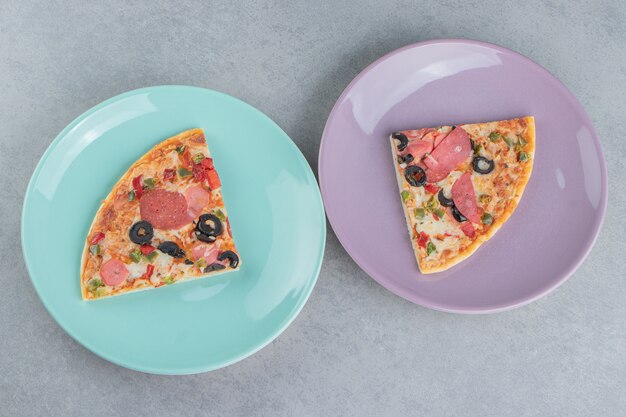 Two platters with pizza slices on marble 