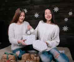 Free photo two pretty young funny women friends smiling and having fun, holding holiday presents, ready for celebration.