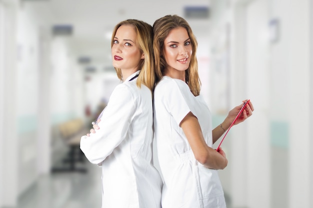 Free Photo two pretty young women doctors, nurses standing back to back in the hospital.