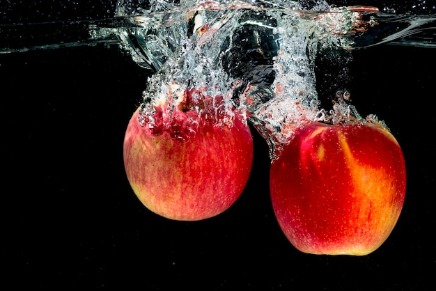 Two red apples splashing in the water