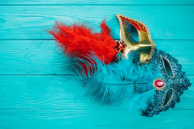 Free photo two red and blue venetian carnival mask on blue wooden table