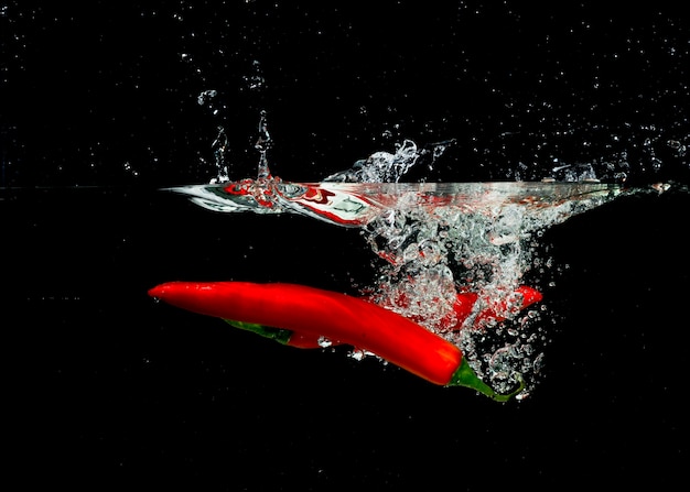 Free photo two red chilies splashing into clear water