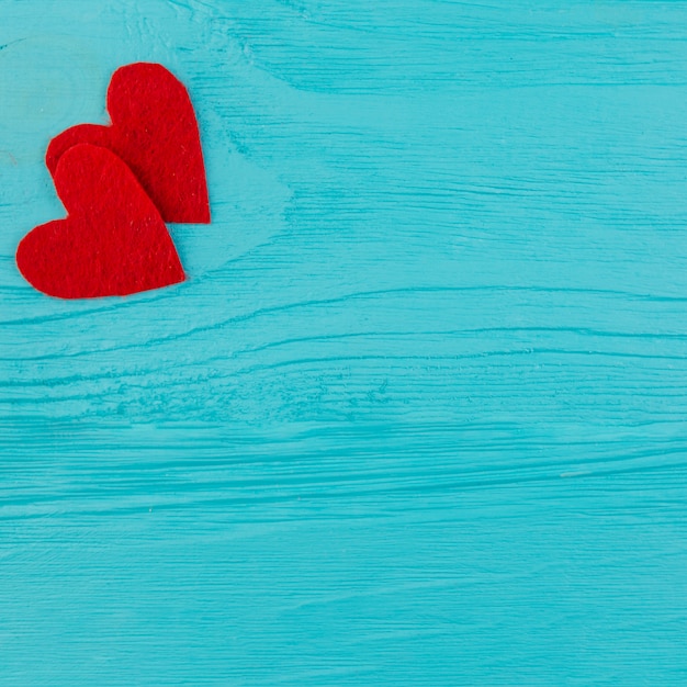 Two red hearts on blue wooden surface