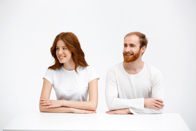 Free photo two redhead adults sit at table, look left smiling