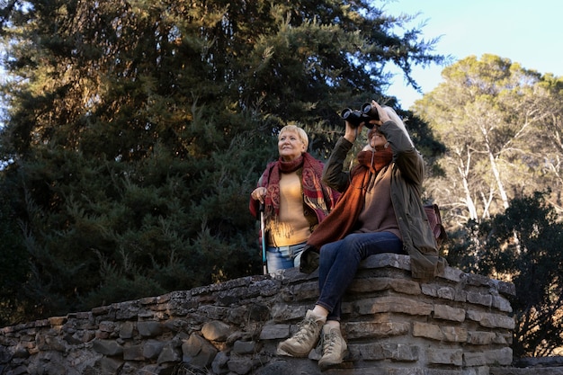 Two senior women enjoying a hike in nature while using binoculars