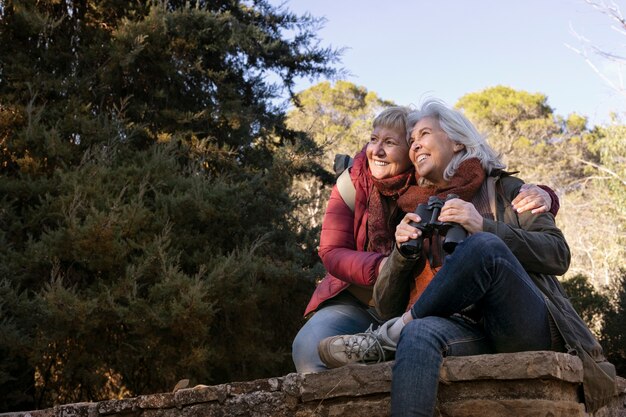 Two senior women enjoying a hike in nature while using binoculars