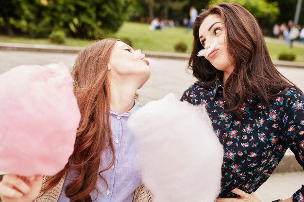 Two sisters eating cotton candy at the park