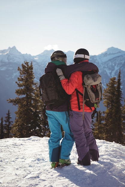 Free Photo two skiers standing together with arm around on snow covered mountain