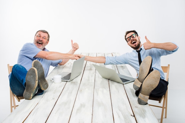 Free photo the two smiling businessmen with legs over table