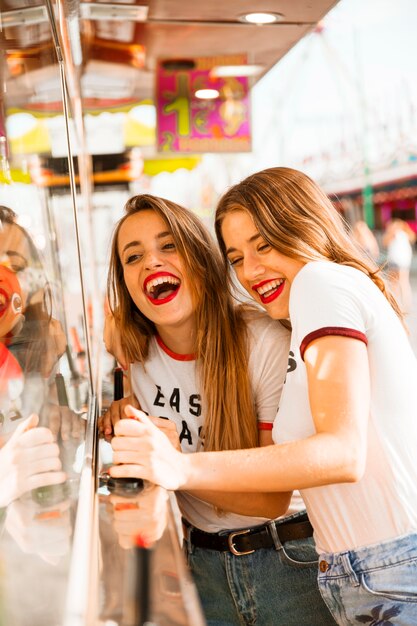 Two smiling female friends having fun at amusement park