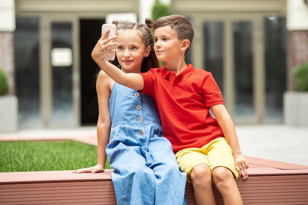 Free photo two smiling kids, boy and girl taking selfie together in town, city in summer day