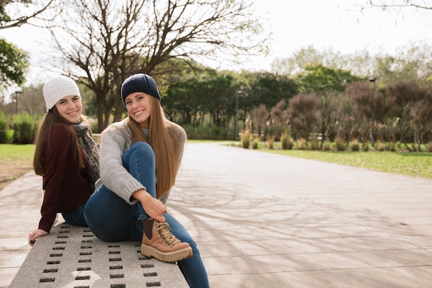 Free photo two smiling women sitting on a bench