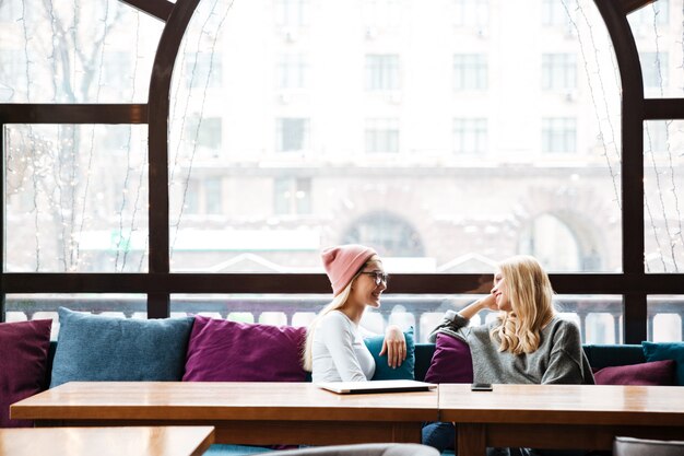 Free Photo two smiling women talking at the table in cafe