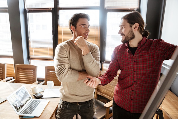 Two smiling young colleagues in office working