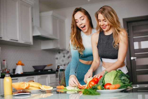 Free Photo two sports girl in a kitchen with vegetables