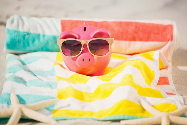 Free photo two starfish and piggy bank with sunglasses on sand