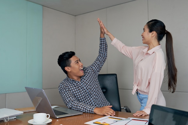 Two startup entrepreneurs giving high five to celebrate successful deal