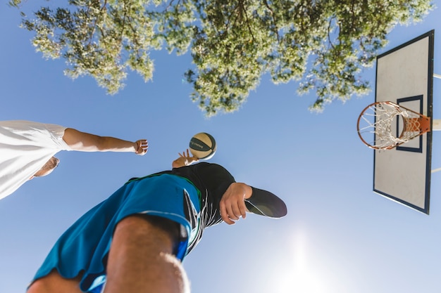 Two street player playing basketball against clear sky