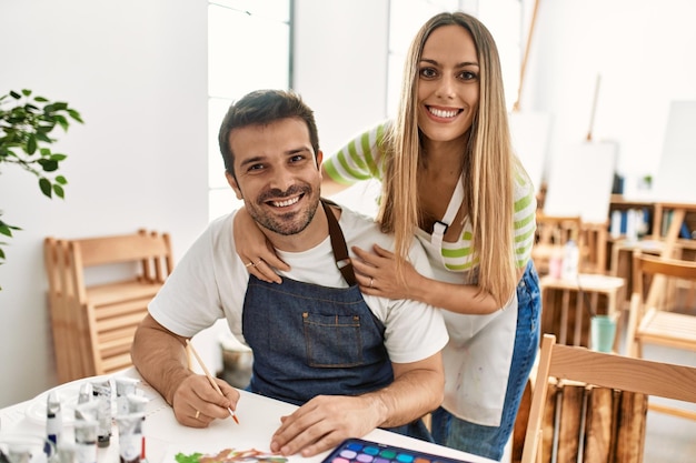 Two students smiling happy painting sitting on the table at art school.