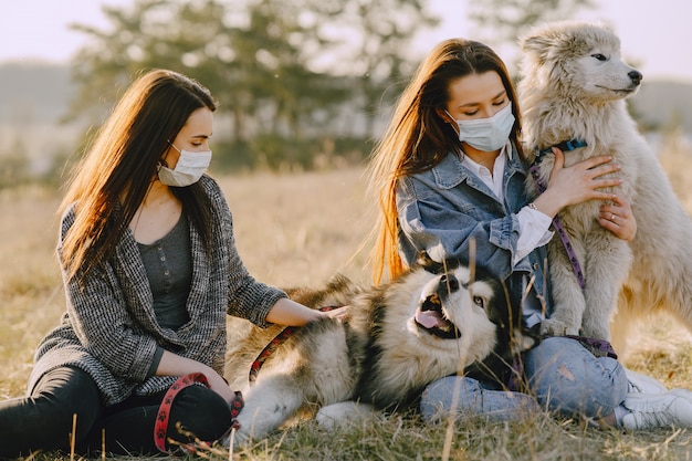 Two stylish girls in a sunny field with dogs