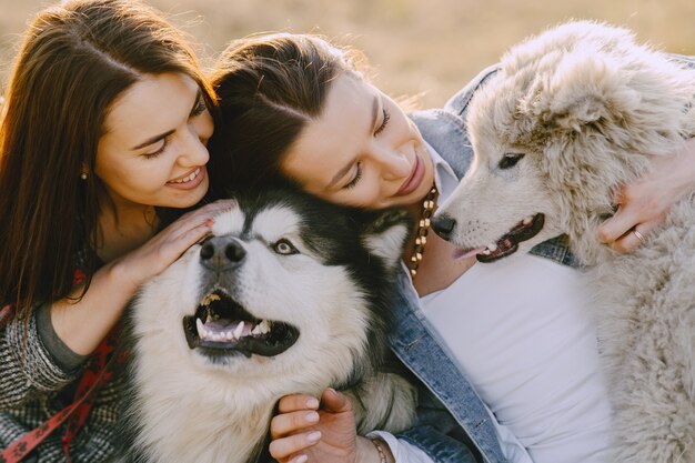 Two stylish girls in a sunny field with dogs