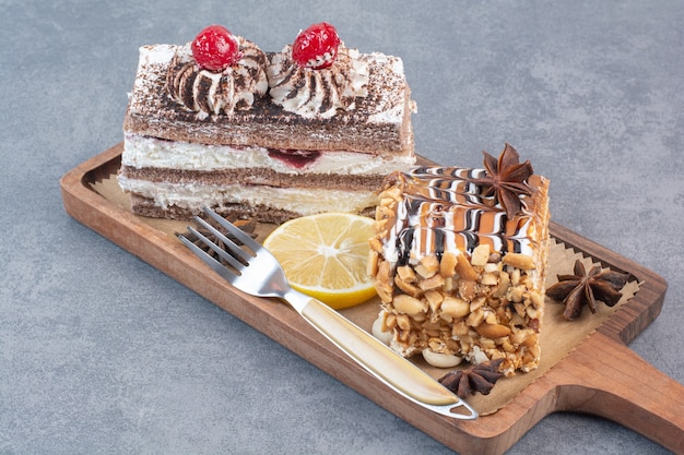 Two sweet delicious piece of cakes with star anise on wooden board.