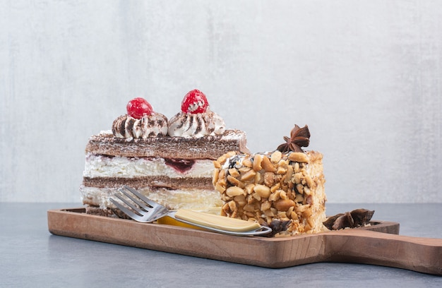 Two sweet delicious piece of cakes with star anise on wooden board.