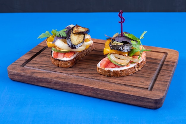 Free Photo two tasty toast with fried vegetables on wooden board.