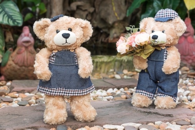 Free photo two teddy bears on garden background