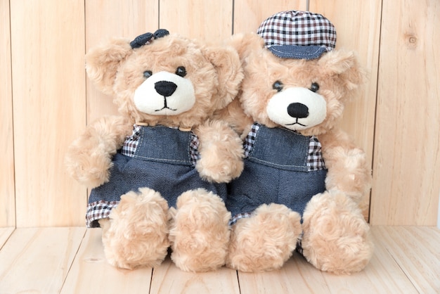 two teddy bears on wood background