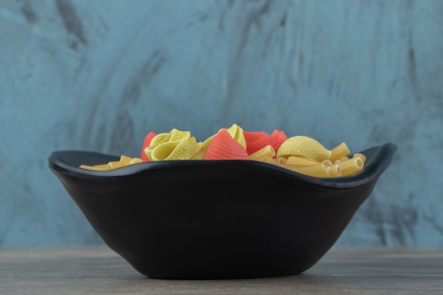 Two types of raw pasta in black bowl.