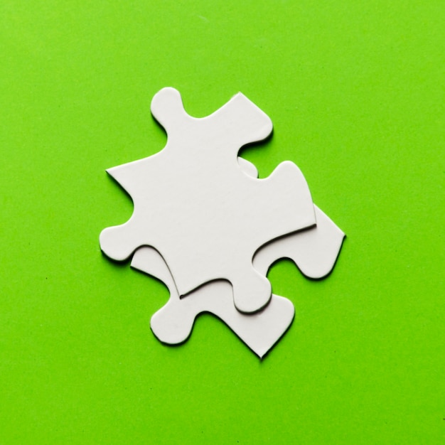 Free photo two white jigsaw puzzle piece on bright green backdrop