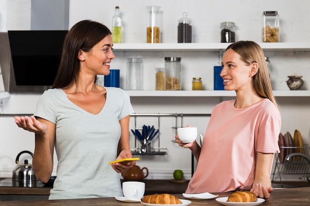 Two women at home chatting over cup of coffee