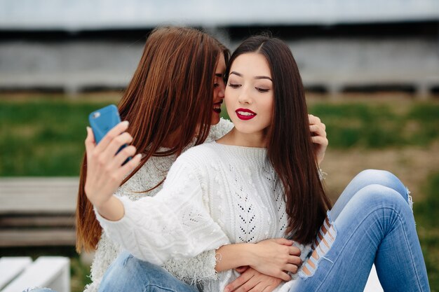 Two women making selfie on the bench in the park