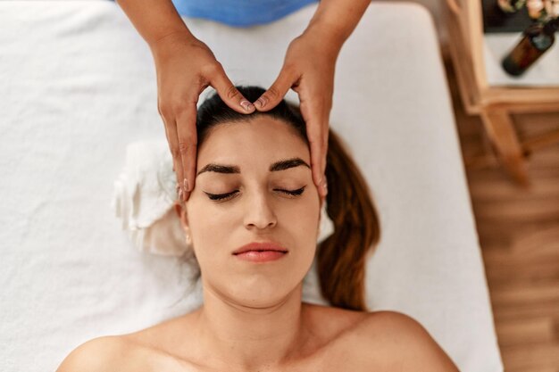 Two women therapist and patient having facial massage session at beauty center