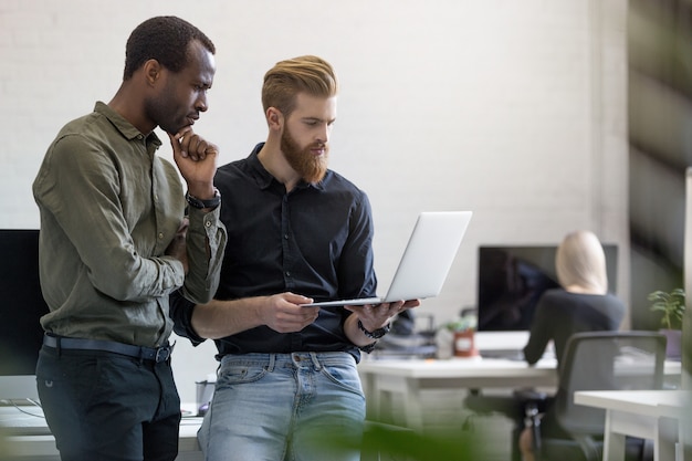 Free photo two worried young business men looking at the laptop