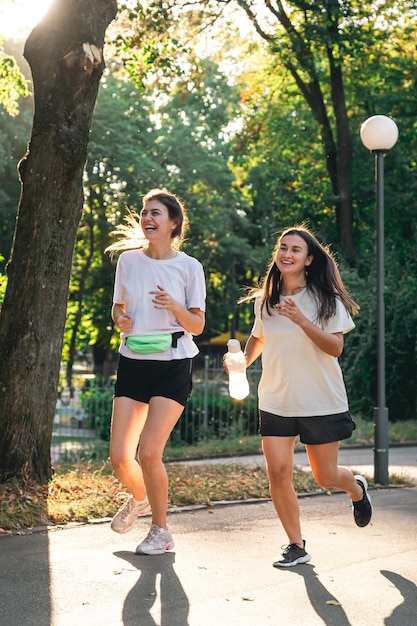 Free photo two young adult woman running in a park