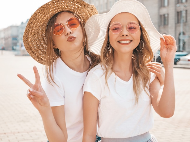 Free Photo two young beautiful blond smiling hipster girls in trendy summer clothes.  .shows peace sign