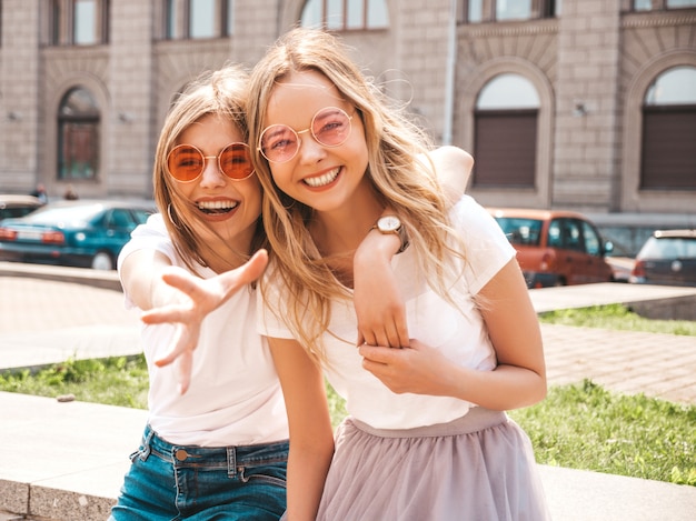 Free photo two young beautiful blond smiling hipster girls in trendy summer white t-shirt clothes.