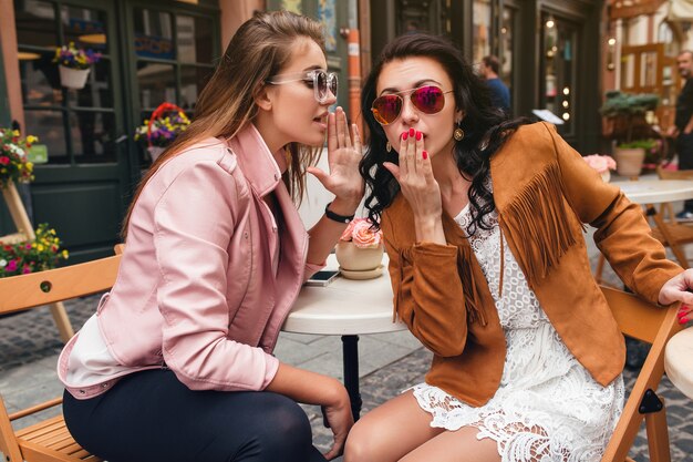 Two young beautiful hipster women sitting at cafe