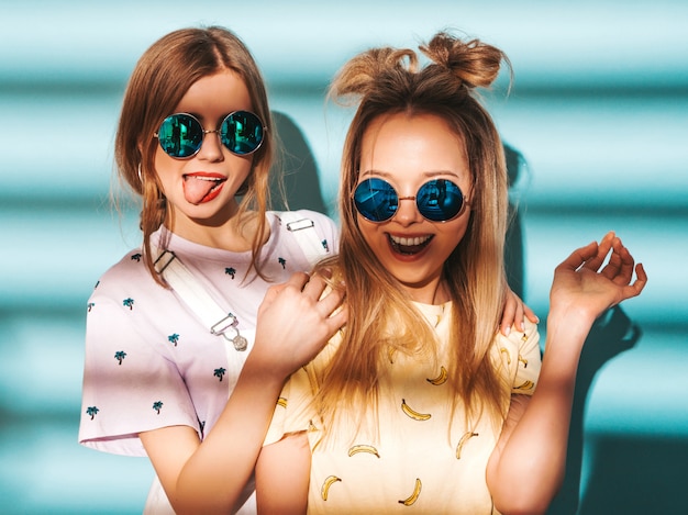 Free Photo two young beautiful smiling blond hipster girls in trendy summer colorful t-shirt clothes. 